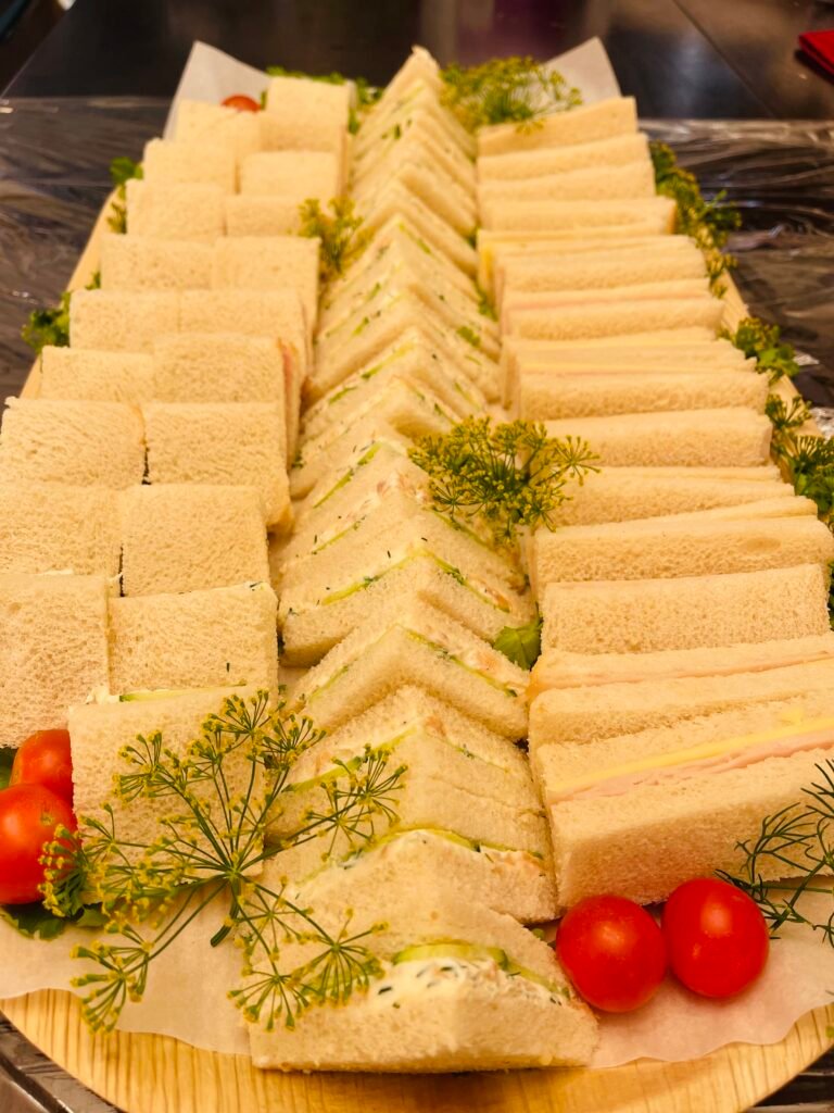 Assorted sandwiches arranged with fruit, vegetables and savory snacks