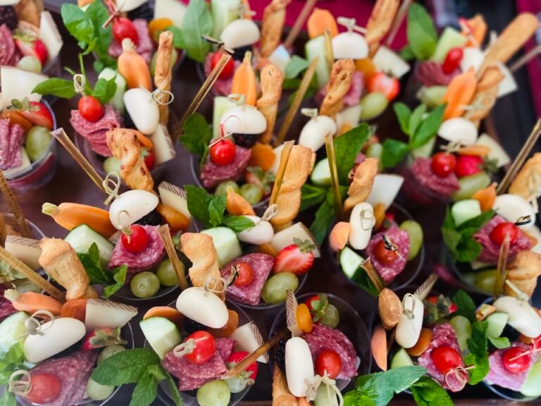 Close-up of sliced cheese, cured meat, grapes, berries and crackers